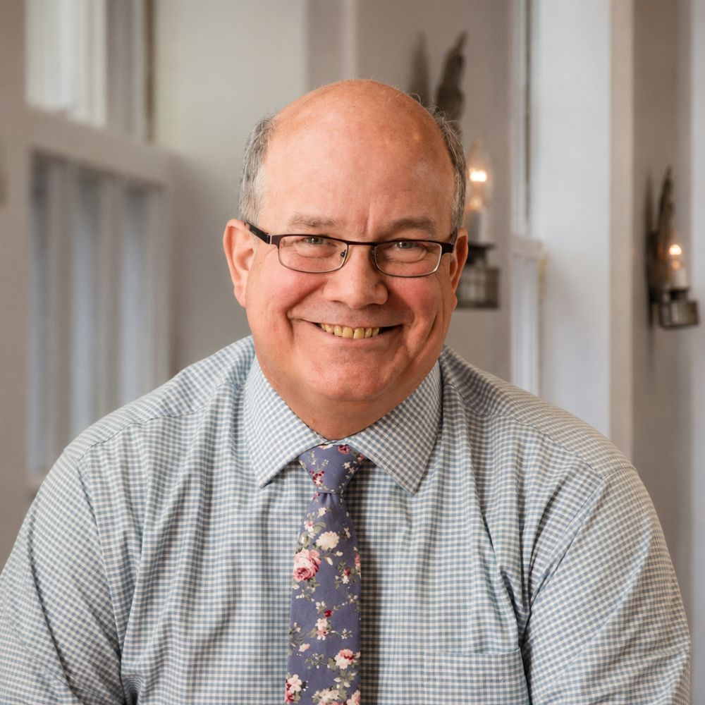 Smiling middle-aged man with glasses in a checkered shirt and floral tie